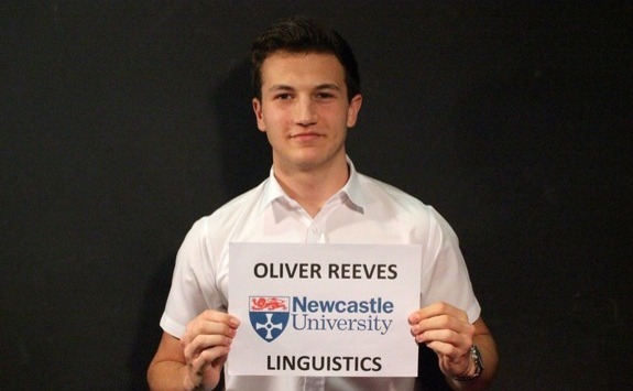 Oliver Reeves as a student holding a sign with his name and the Newcastle Uni logo